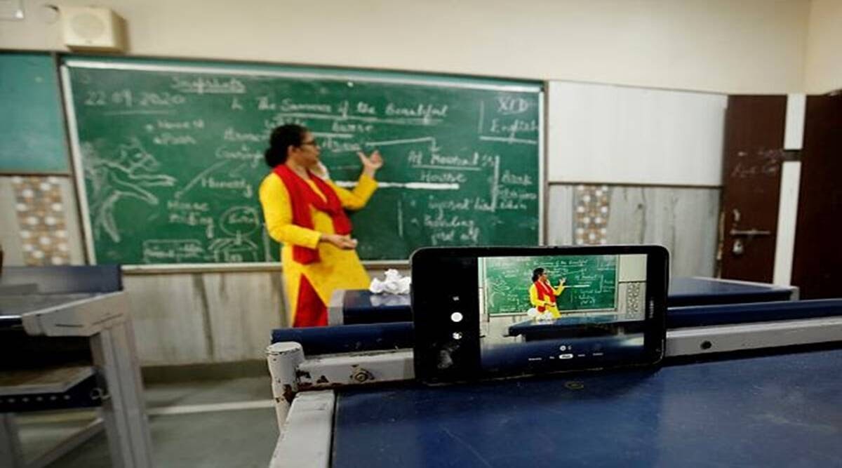 teacher stands in front of board while streaming live from a mobile phone