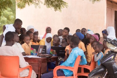 Community of people sitting around a laptop learning
