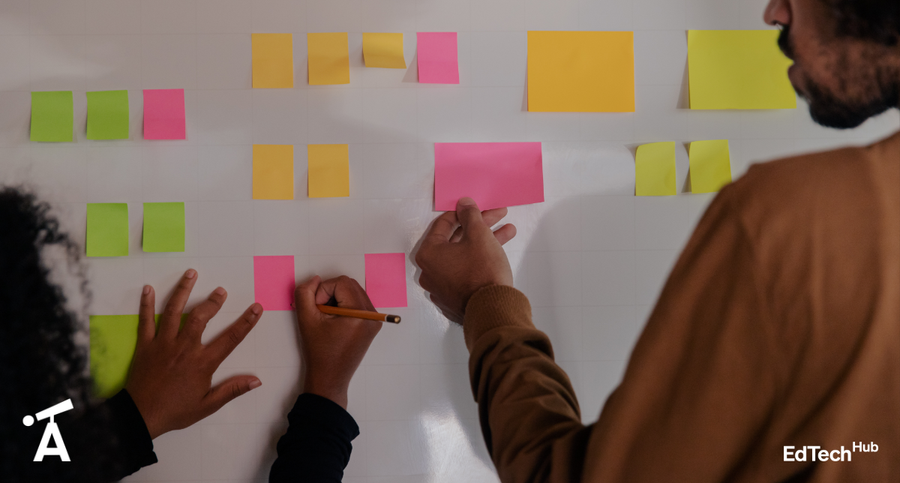 People working together on a whiteboard collaborating using sticky post it notes